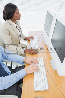 Business colleagues using computers at desk