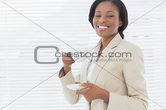 Elegant smiling businesswoman with a cup of tea in office