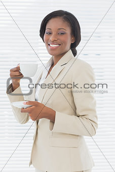 Elegant smiling businesswoman with tea cup in office