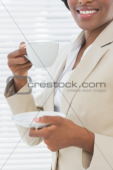 Mid section of smiling businesswoman with a cup of tea