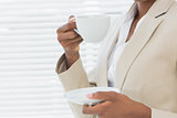 Mid section of elegant businesswoman with tea cup in office