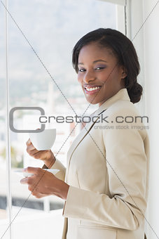 Elegant smiling businesswoman with a cup of tea in office