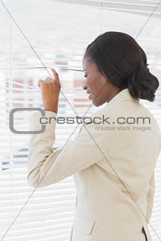 Businesswoman peeking through blinds in office