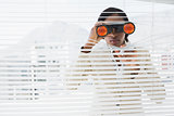 Businessman peeking with binoculars through blinds