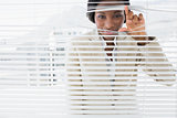 Portrait of a businesswoman peeking through blinds