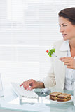 Businesswoman using computer while eating salad at desk