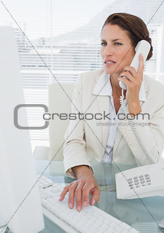 Businesswoman using computer and phone