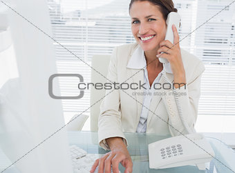 Smiling businesswoman using computer and phone