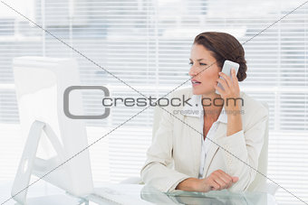 Businesswoman using computer and cellphone at desk