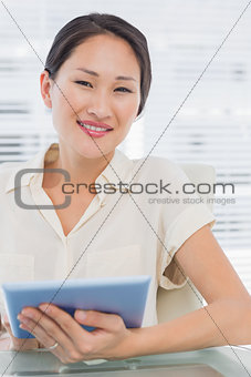 Smiling businesswoman using digital tablet at desk