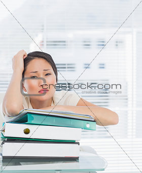 Bored businesswoman with stack of folders at desk