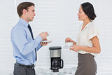 Business couple with tea cups chatting in office