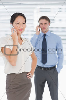 Businesswoman and man using cellphones in office