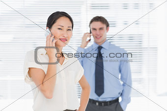 Businesswoman and man using cellphones in office