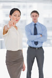 Businesswoman pointing towards camera with man in office
