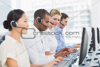 Business colleagues with headsets using computers at desk