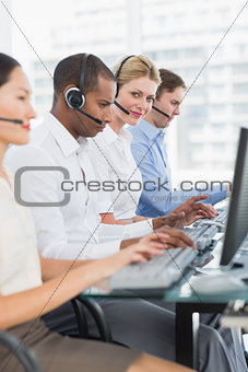 Business colleagues with headsets using computers at desk