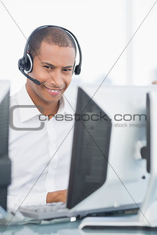 Male executive with headset using computer at desk