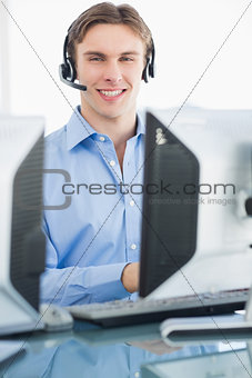 Male executive with headset using computer at desk
