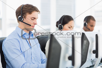 Business colleagues with headsets using computers in office