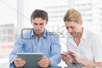 Businessman and woman using digital tablet and cellphone at office