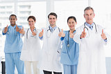 Confident doctors gesturing thumbs up at hospital
