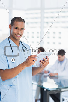 Surgeon using digital tablet with group around table in hospital
