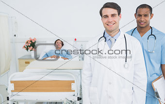 Two smiling doctors with patient in hospital