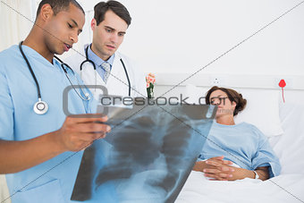 Doctors examining xray by patient in hospital