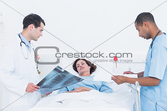 Doctors examining xray by patient in hospital