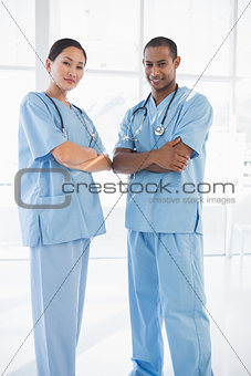 Confident surgeons with arms crossed in hospital