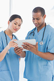 Male and female surgeons looking at digital tablet