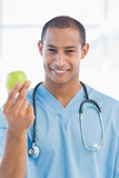 Portrait of a smiling surgeon holding an apple
