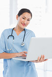 Smiling female surgeon using a laptop