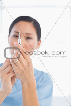 Serious female doctor holding an injection
