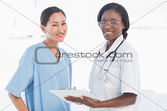 Female doctor and surgeon with report in hospital