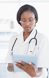 Concentrated female doctor using digital tablet