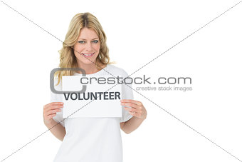 Portrait of a smiling young female volunteer holding placard