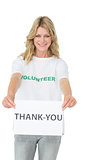 Smiling young female volunteer holding thank you paper