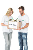 Smiling young couple carrying donation box