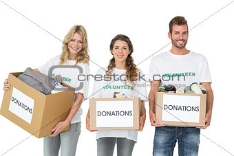 Portrait of three smiling young people with donation boxes
