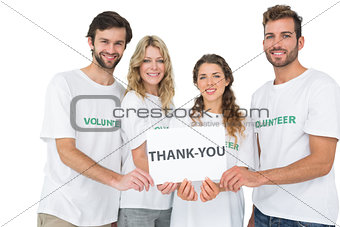 Portrait of happy volunteers holding thank you board