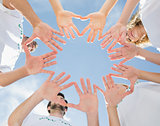 Volunteers with hands together against blue sky