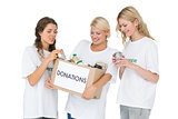 Three smiling young women with donation box