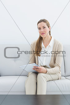 Serious female financial adviser sitting on sofa