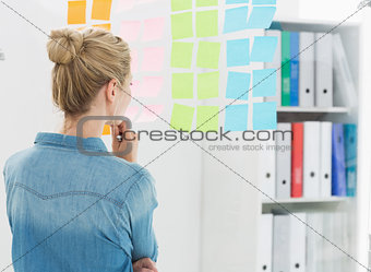 Rear view of a female artist looking at colorful sticky notes