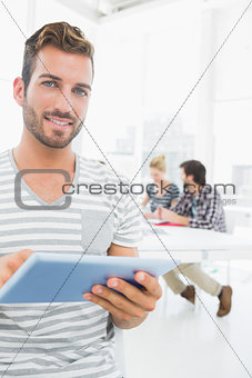Man using digital tablet with colleagues in background