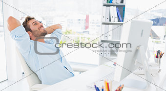 Casual man resting with hands behind head in office