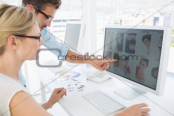 Side view of photo editors working on computer