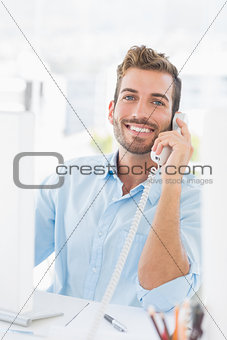 Smiling young man using phone and computer